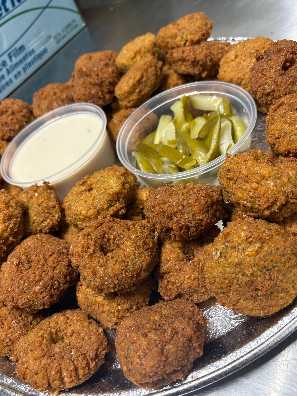 Platter of golden falafel with tahini sauce and pickles